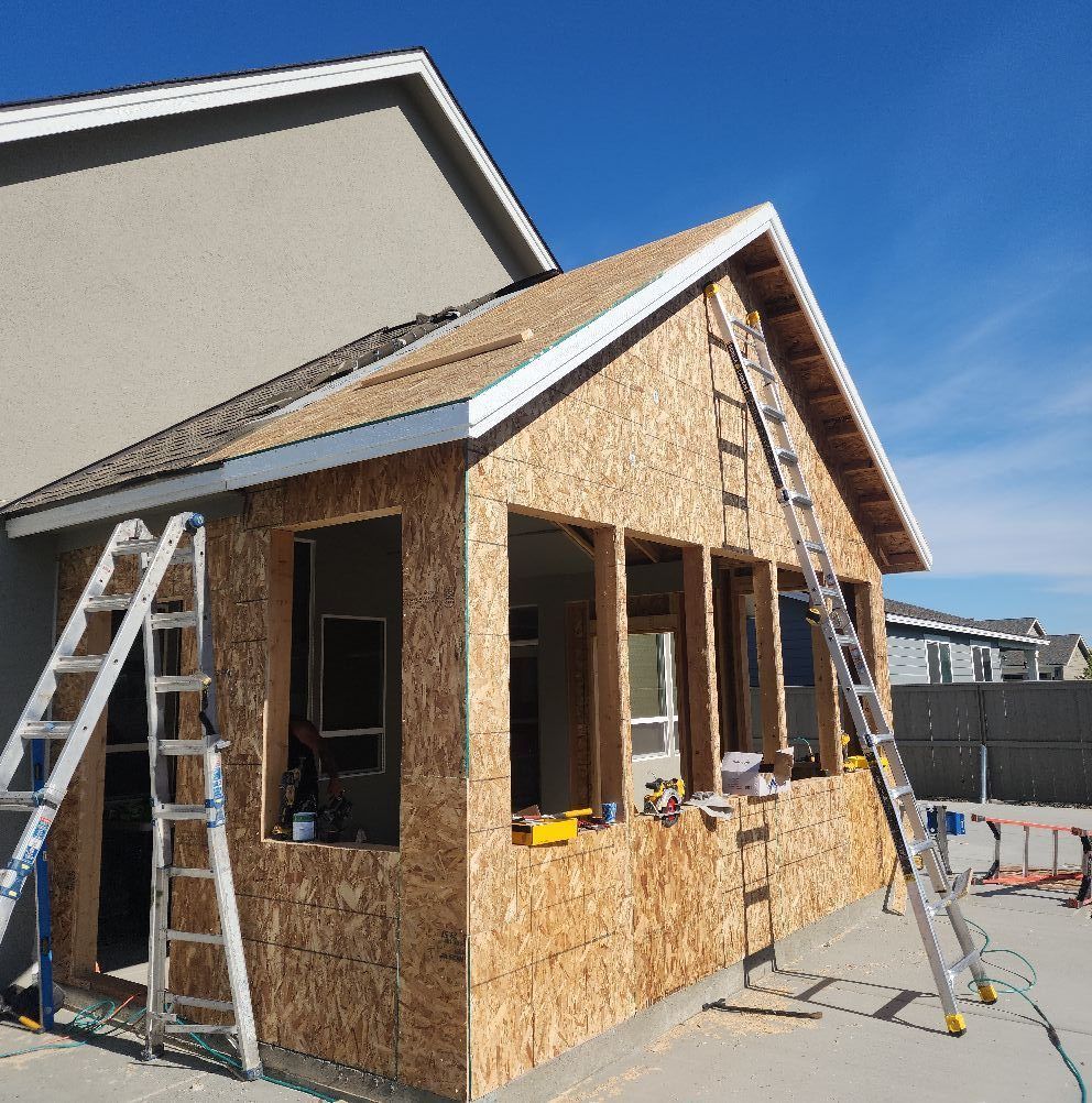 Construction of a wooden room addition attached to a house; unfinished with ladders and materials.