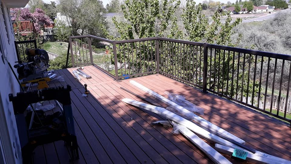 Deck with brown composite decking, black railing, and white trim pieces.