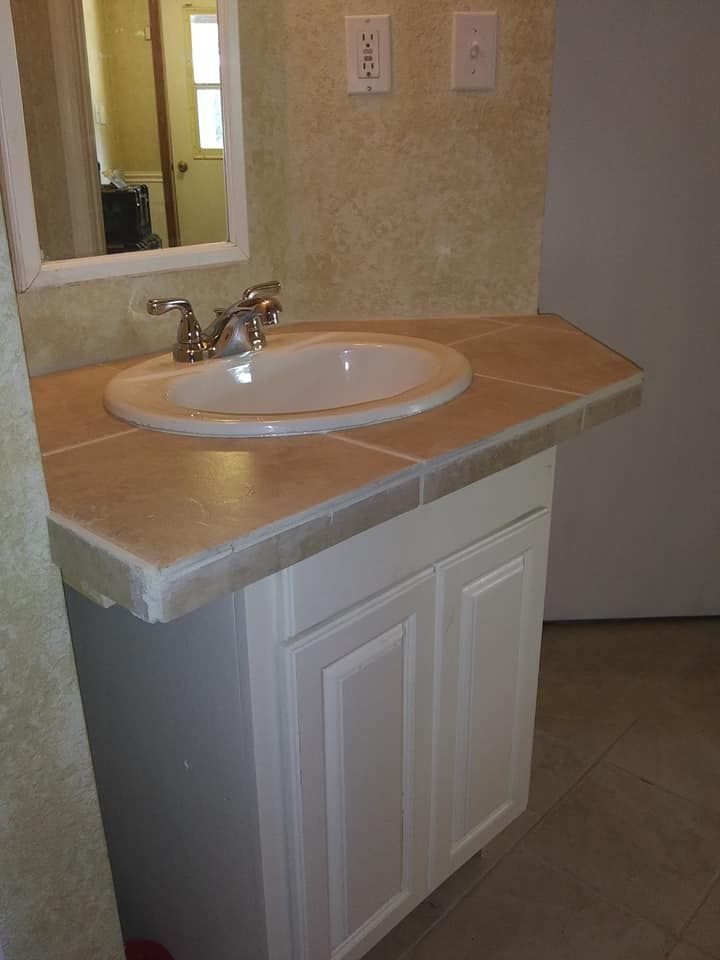 Bathroom vanity with a white cabinet, tan countertop, and oval sink.
