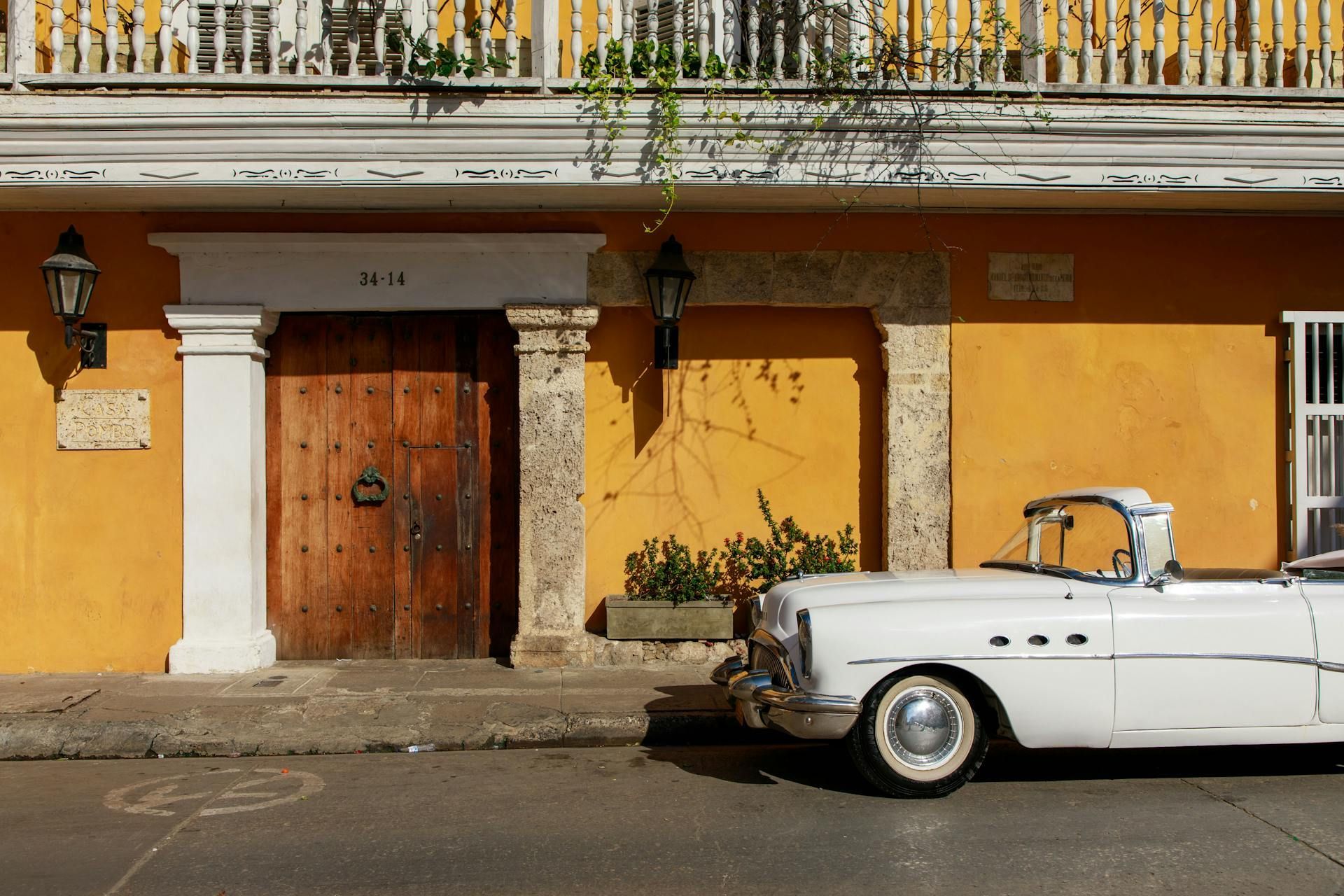 Un coche blanco está aparcado delante de un edificio amarillo.
