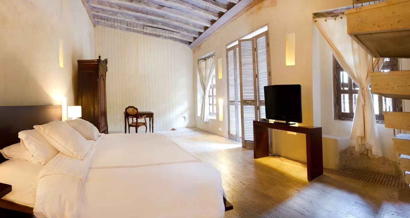 Un dormitorio con una cama grande, televisión y escaleras.