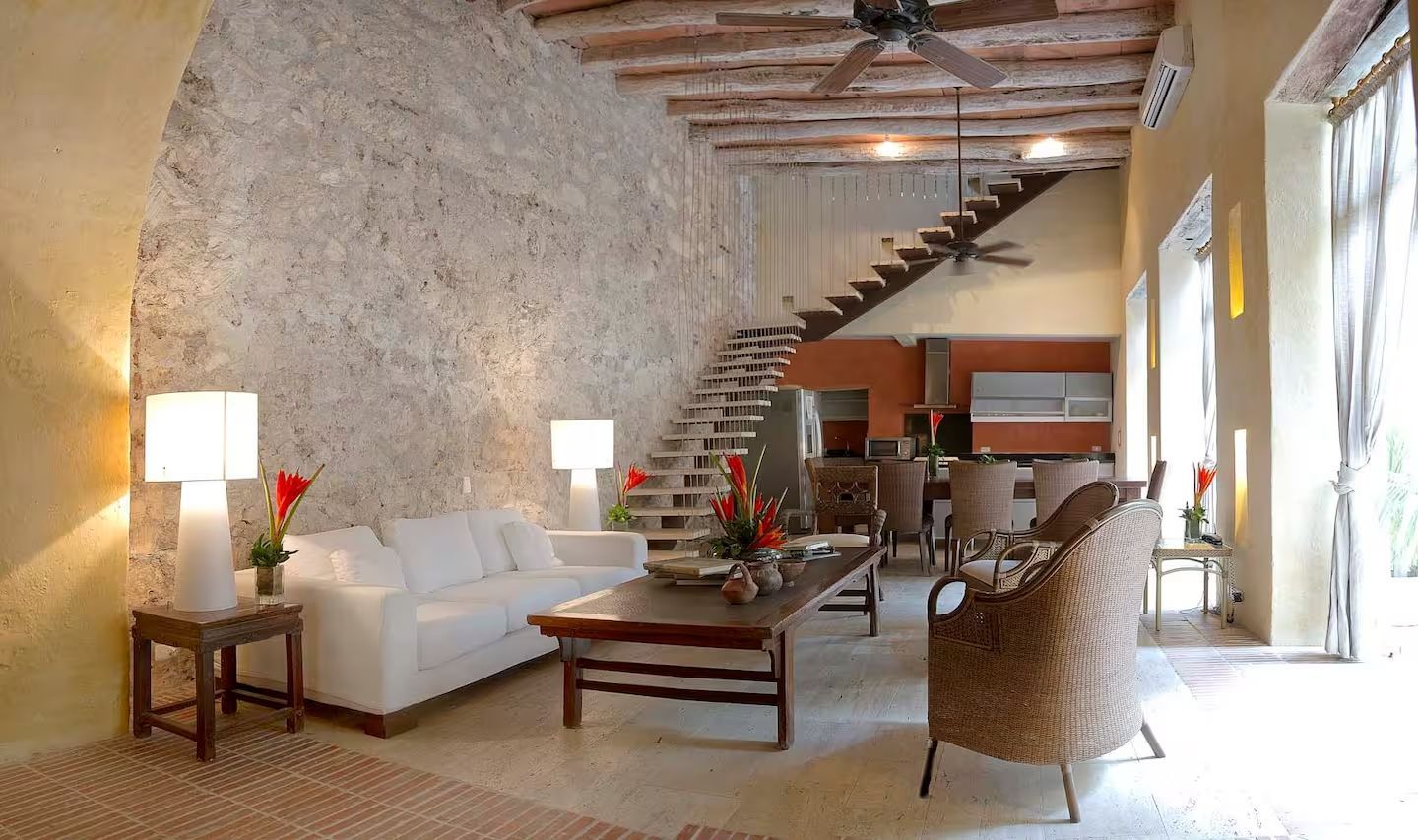 Una sala de estar con un sofá blanco y sillas de mimbre.