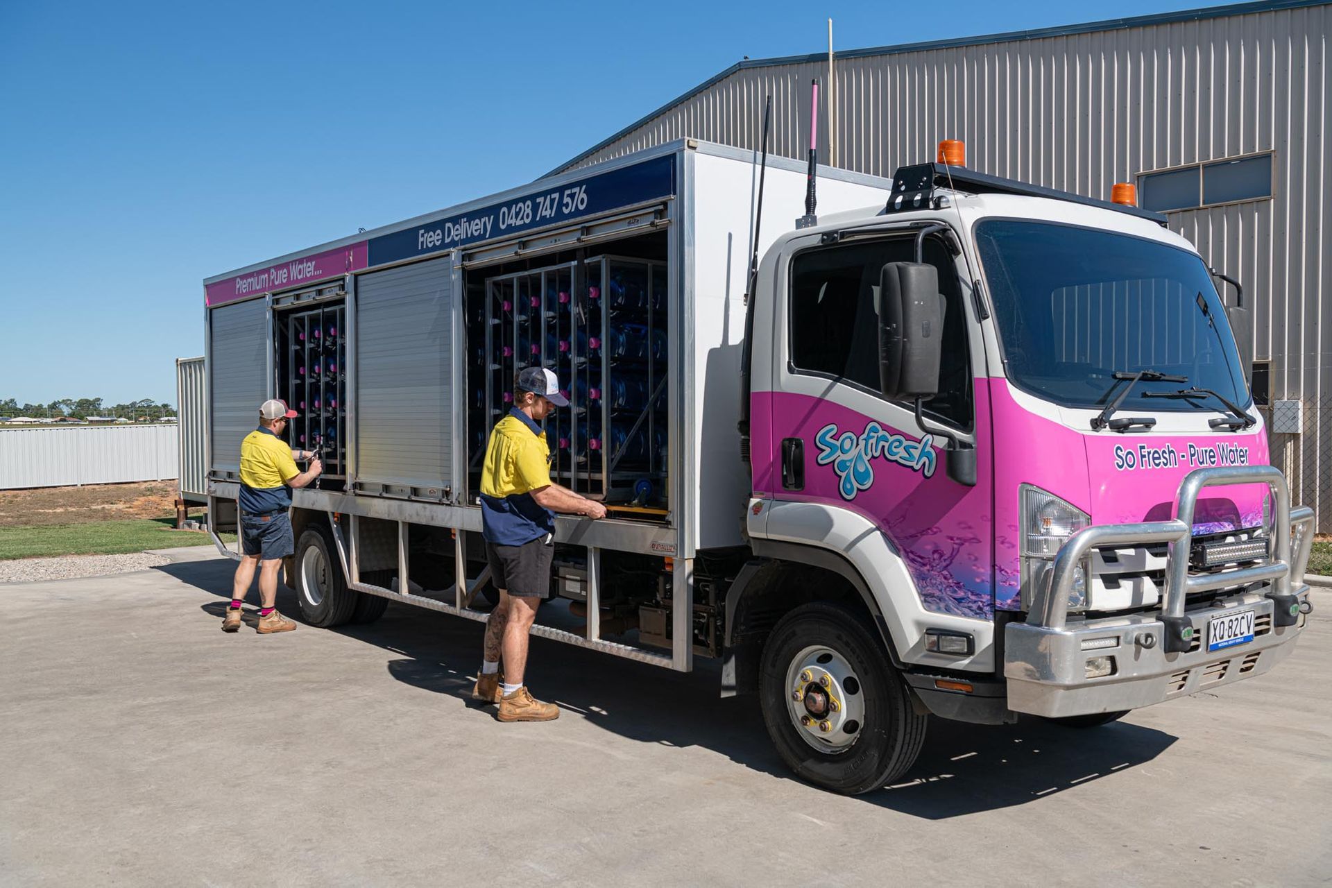 Two workers beside a pink-and-white box truck outside an industrial building — So Fresh Wide Bay in Bargara, QLD