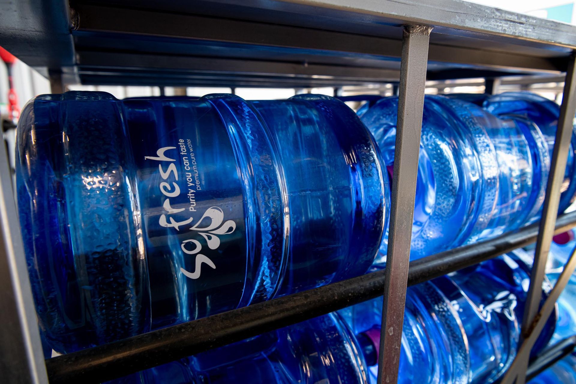 Blue Water Bottles Stacked on Metal Racks in a Storage Area — So Fresh Wide Bay in Thabeban, QLD