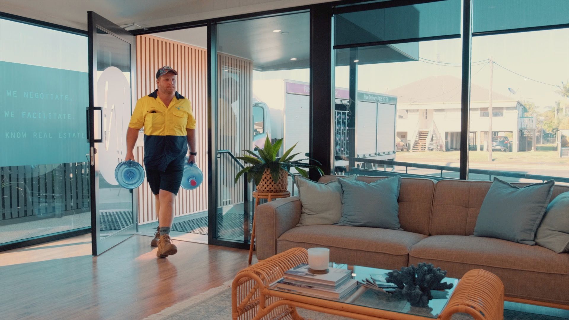 Man in Yellow Shirt and Blue Shorts Walking Into a Modern Living Room — So Fresh Wide Bay in Bargara, QLD