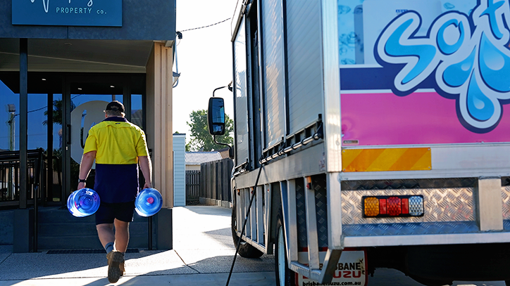 Person Carrying Blue Buckets Walks Between a Building Entrance — So Fresh Wide Bay in Thabeban, QLD