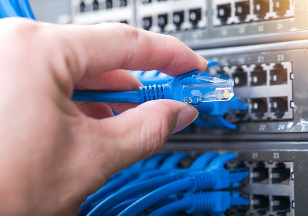 A Person is Plugging a Blue Cable Into a Server — Advantage Communications & Electrical in Maroochydore, QLD