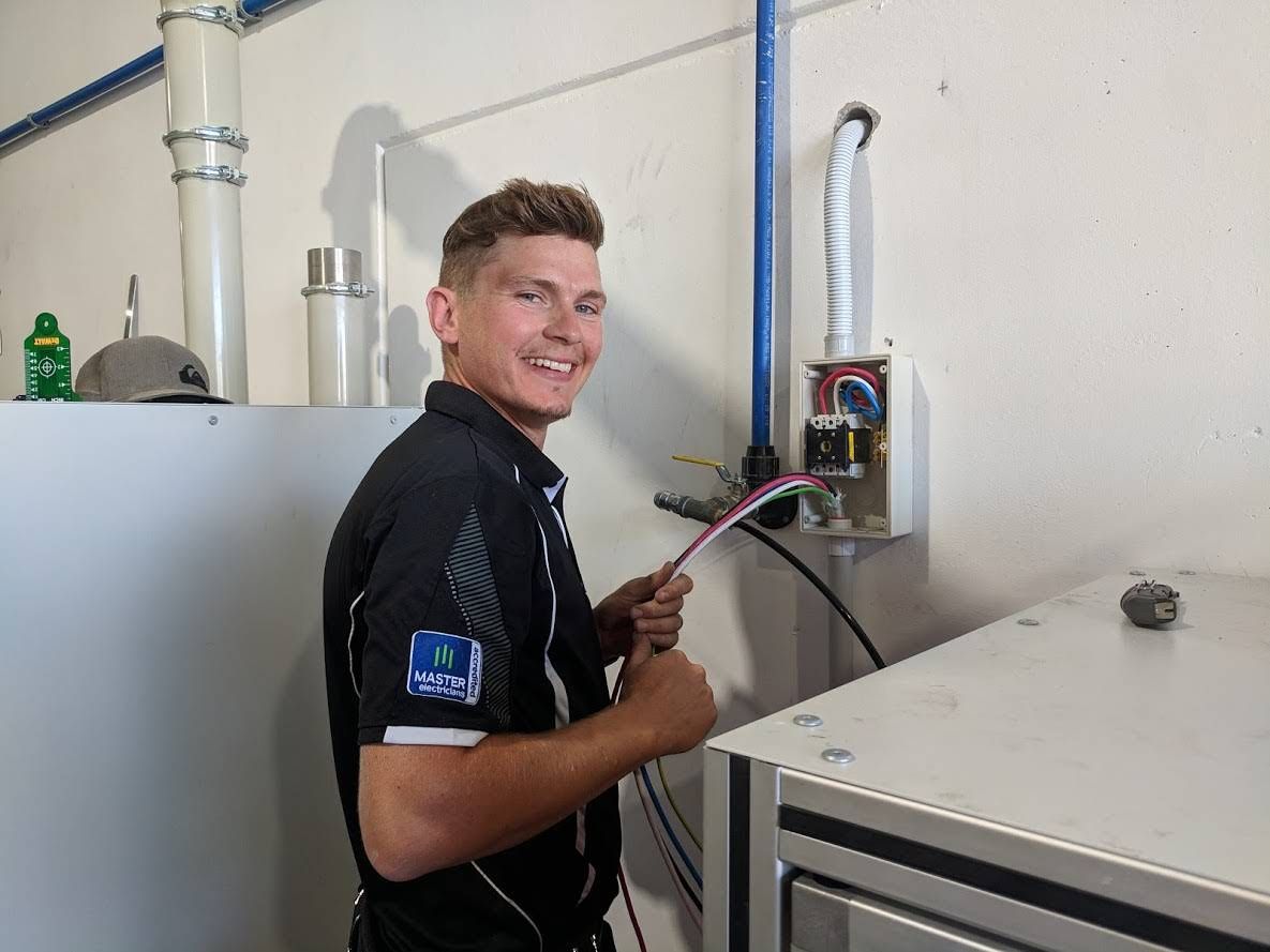 A Man in a Black Shirt is Working on a Machine — Advantage Communications & Electrical in Maroochydore, QLD