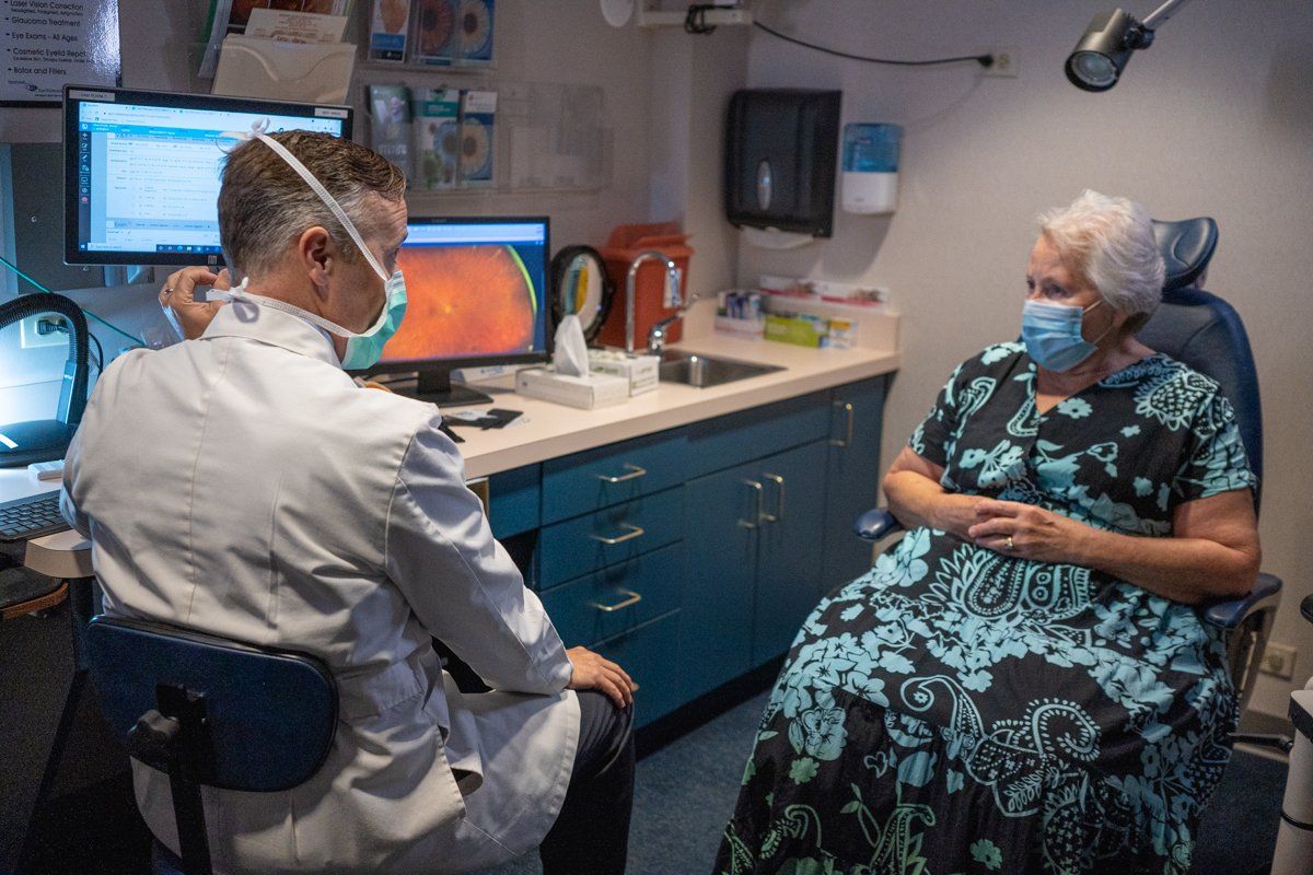 A doctor is talking to a patient wearing a mask in an office.