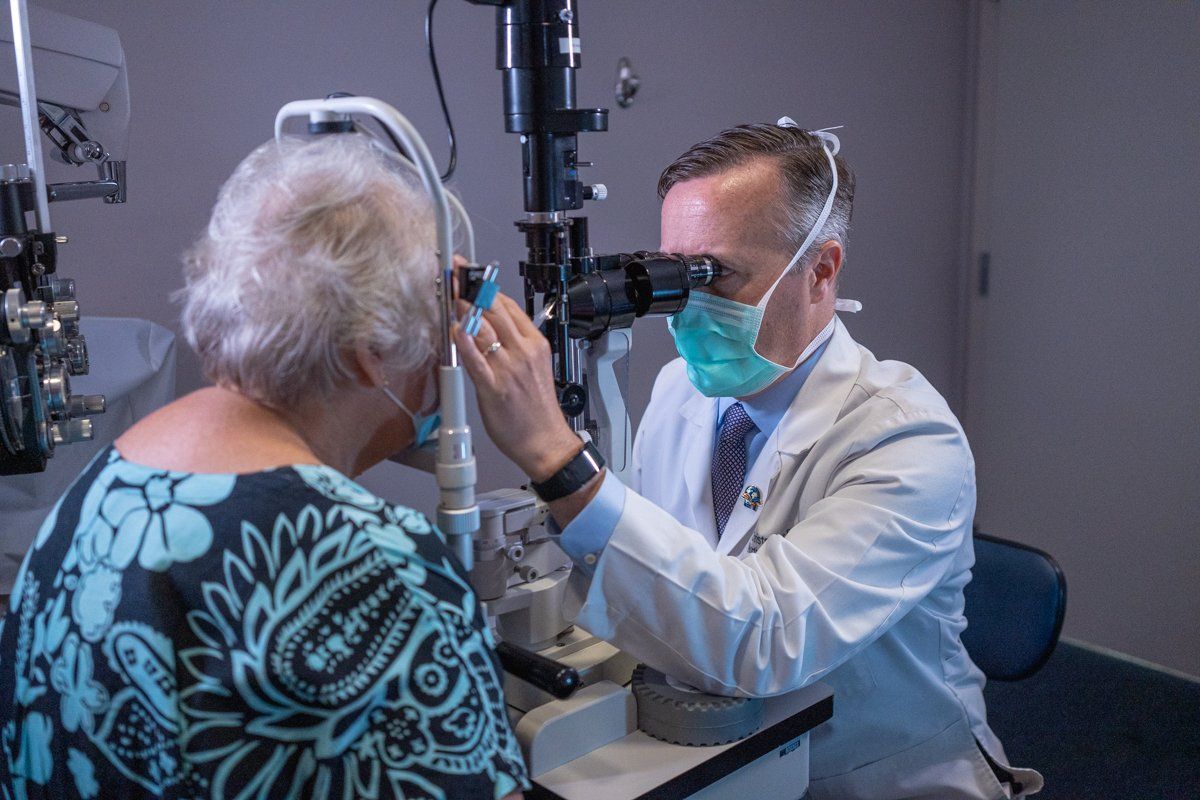A doctor is examining a patient 's eye with a microscope.