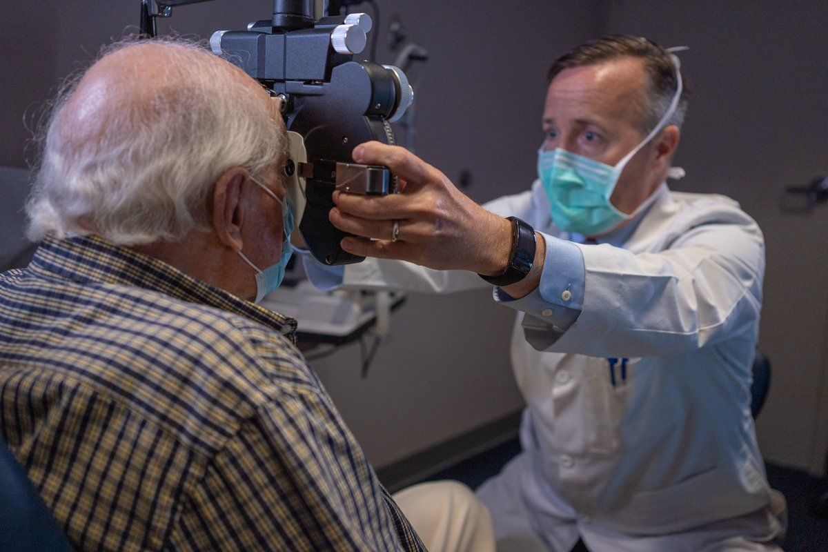 An older man is getting his eyes examined by an ophthalmologist.