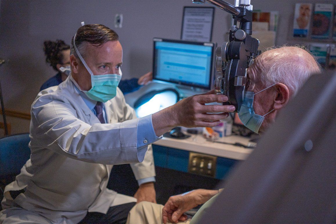 A doctor wearing a mask is examining a patient 's eye.