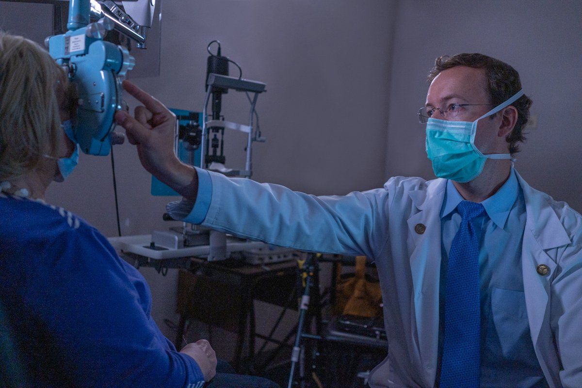 A doctor wearing a mask is examining a patient 's eye.