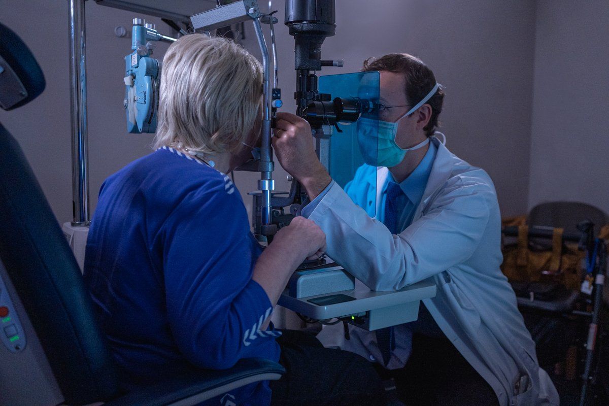 A man is examining a woman 's eye with an ophthalmologist.