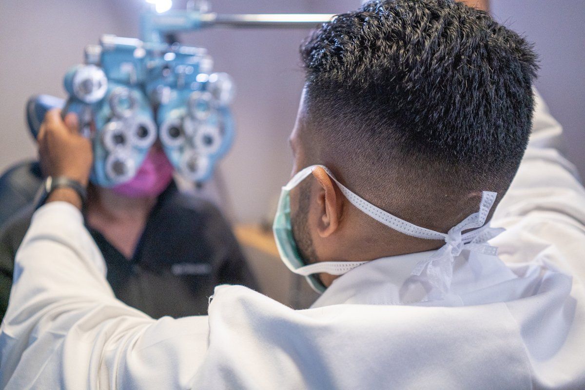 A man wearing a mask is getting his eyes checked by an ophthalmologist.