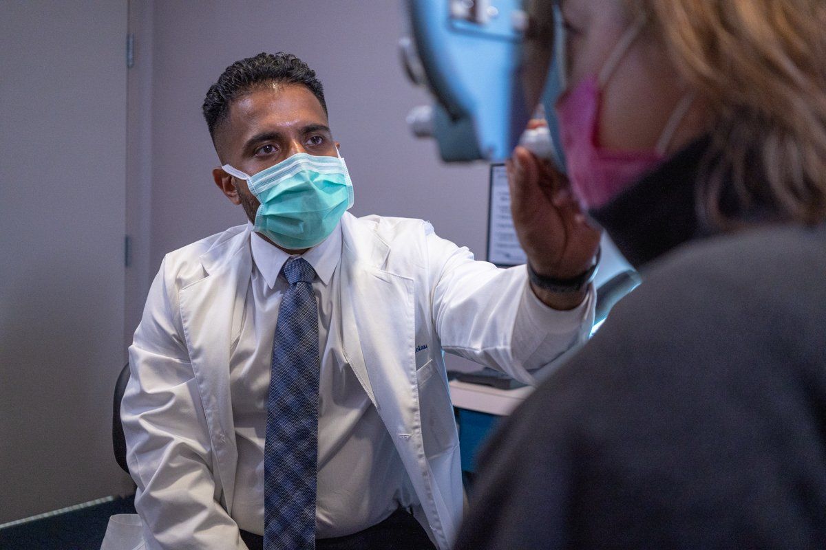 A doctor wearing a mask is examining a patient 's eye.