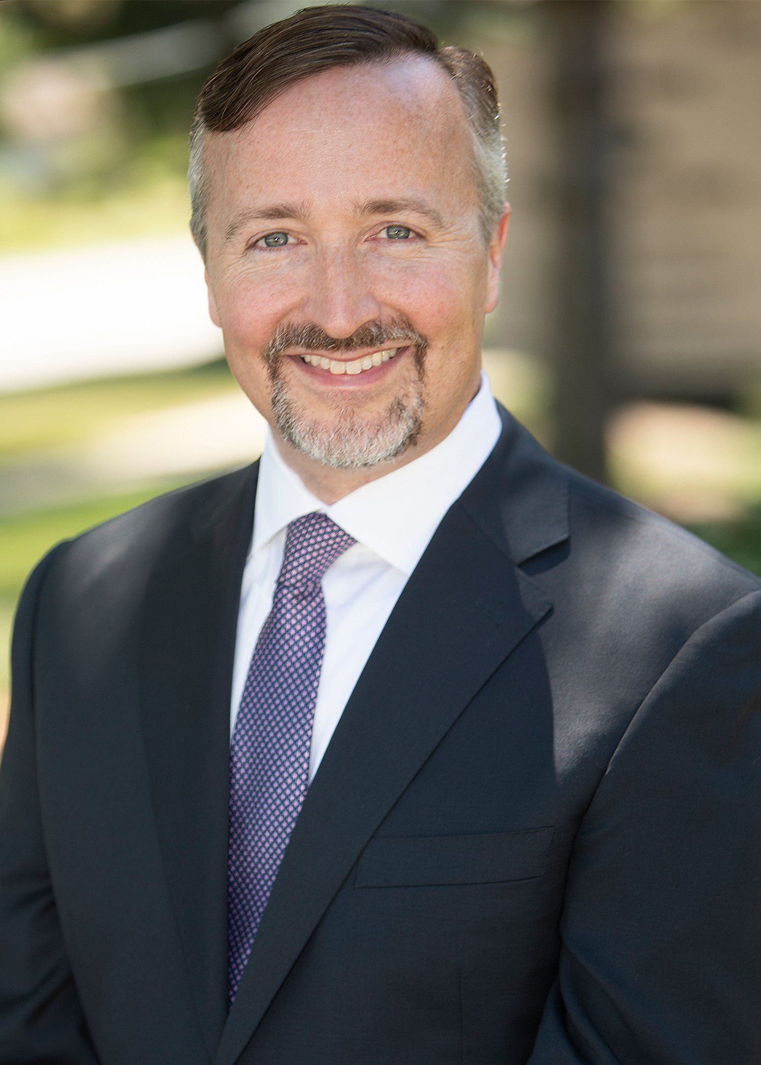A man in a suit and tie is smiling for the camera.
