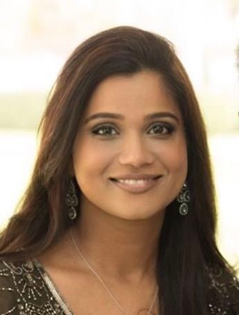 A man in a suit and white shirt is smiling for the camera.