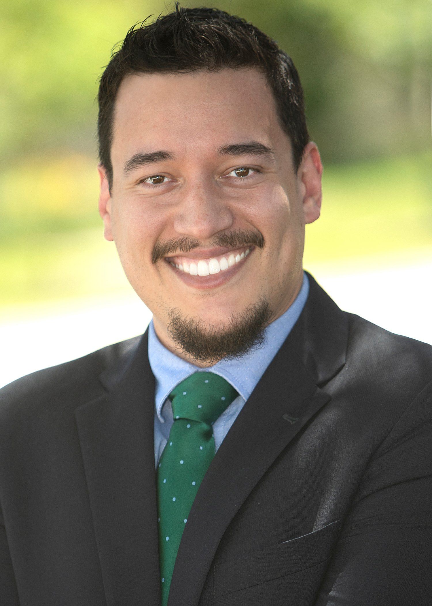 A man in a suit and tie is smiling for the camera