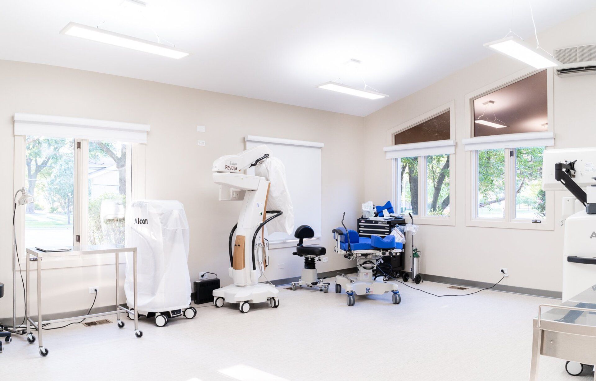 An empty operating room with a robotic arm and a surgical table.
