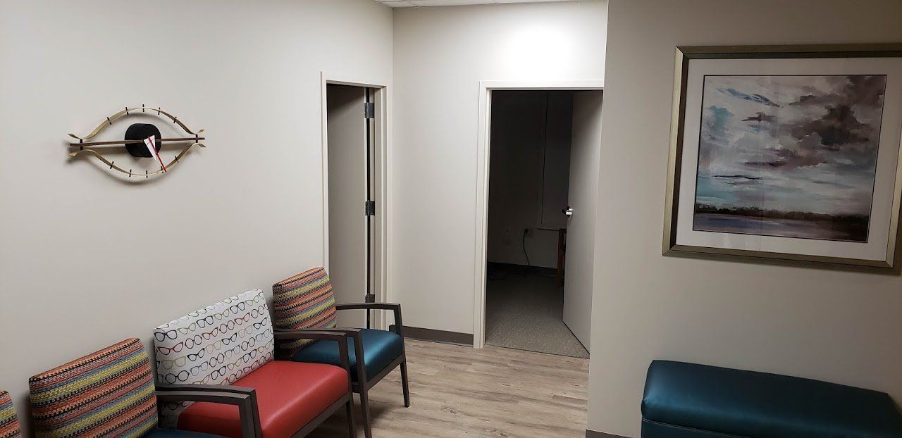 A waiting room with chairs and a painting on the wall.