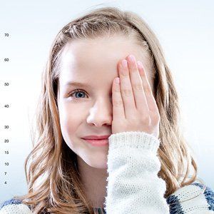 A little girl is covering her eye with her hand