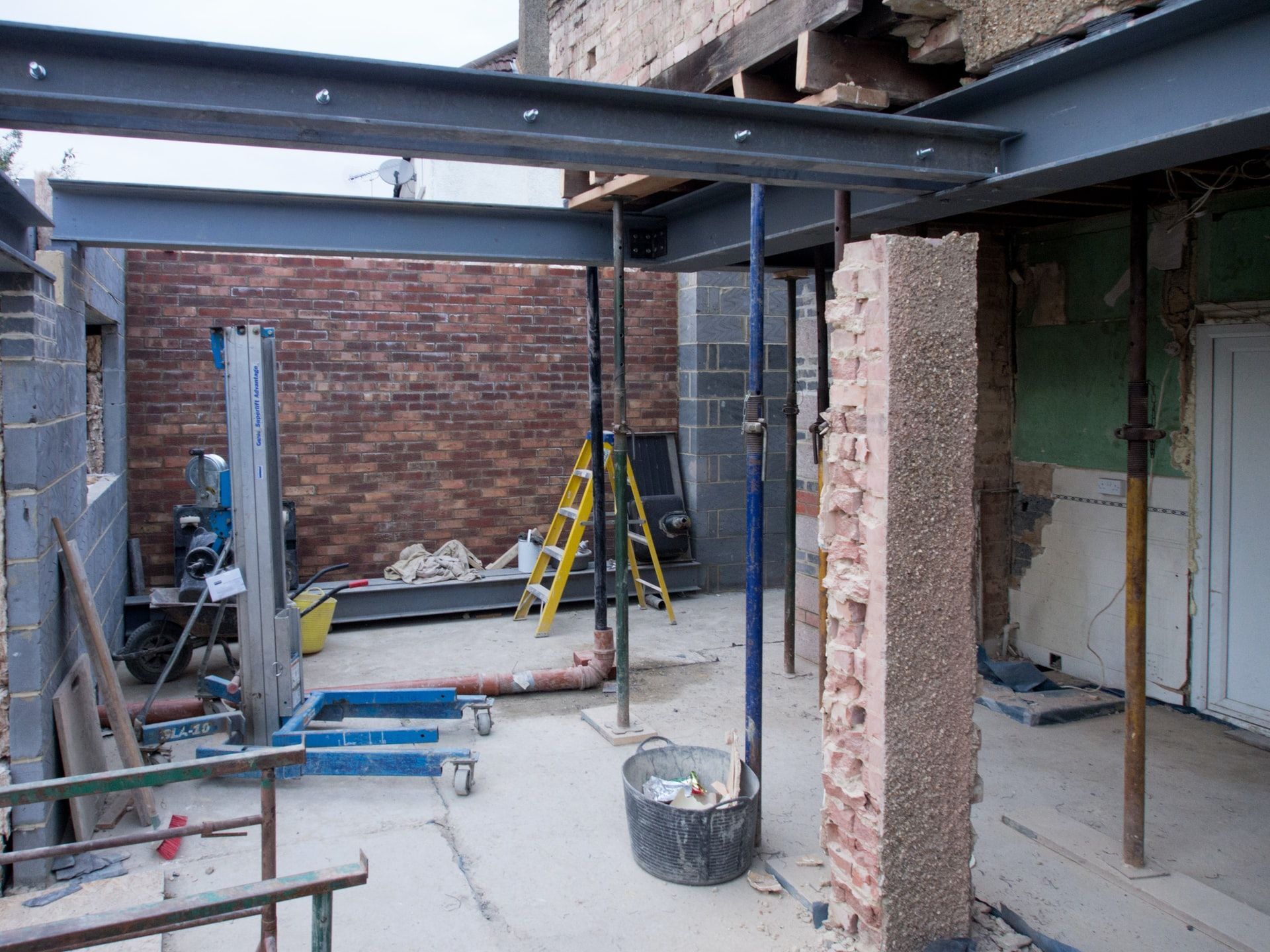 Construction site with steel beams, support posts, and brick walls.