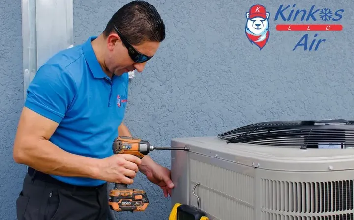 A man is working on an air conditioner with a drill.