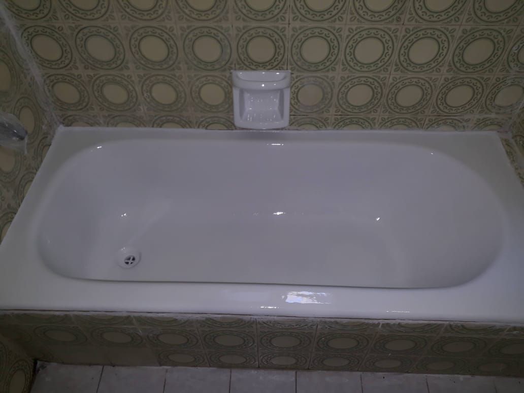 Bañera blanca en un baño alicatado con jabonera encima.