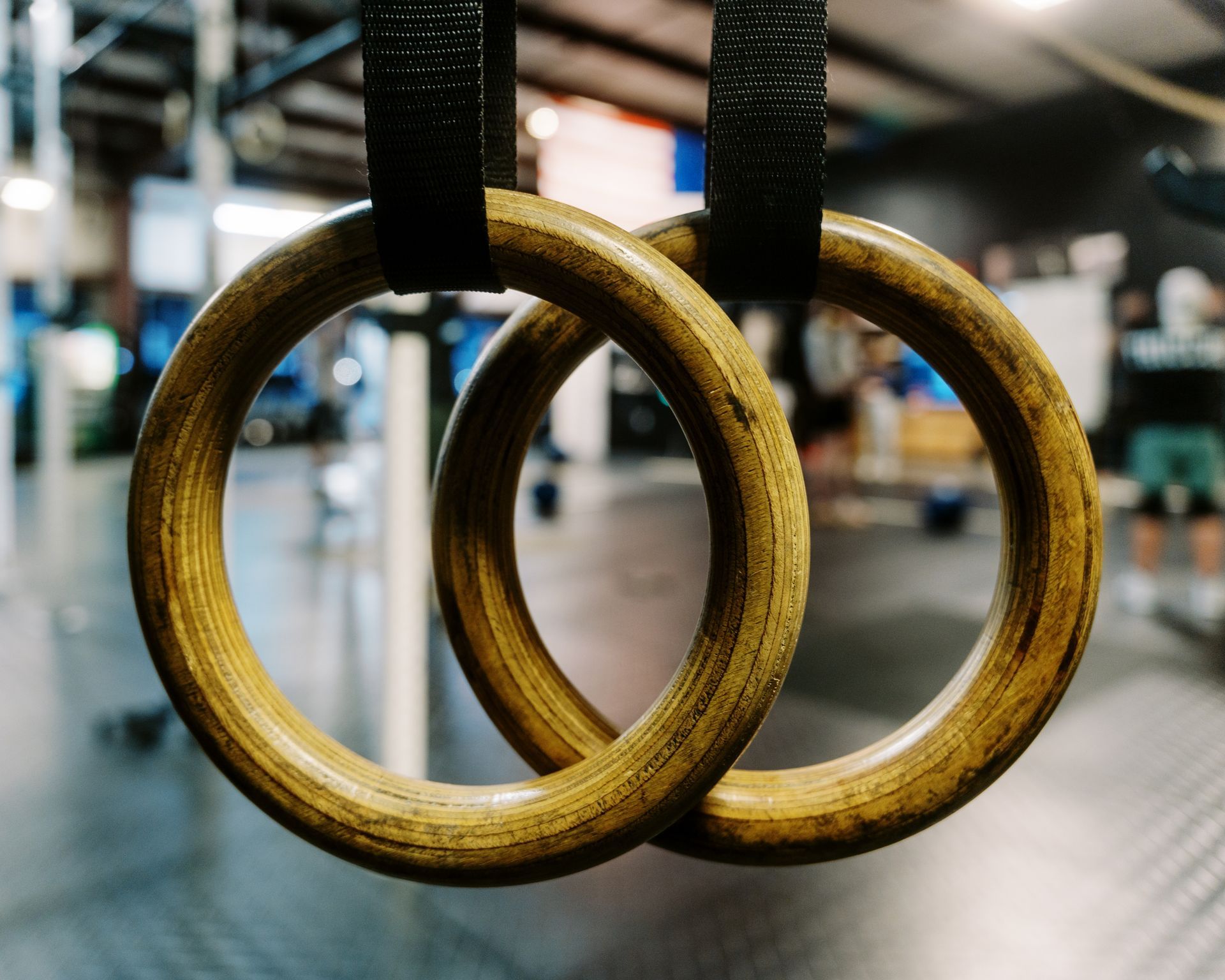 Two wooden gymnastics rings hanging from black straps at Be Somebody Gym in Knoxville, TN