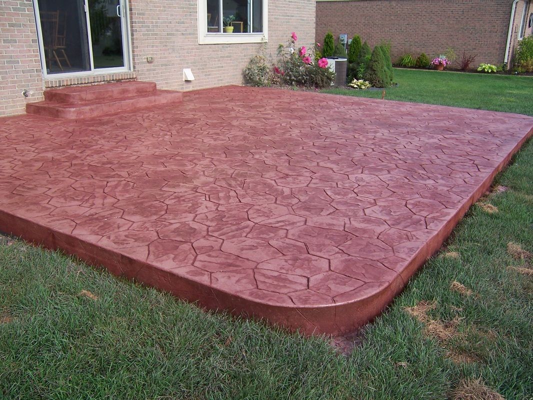 A red concrete patio in front of a brick house.