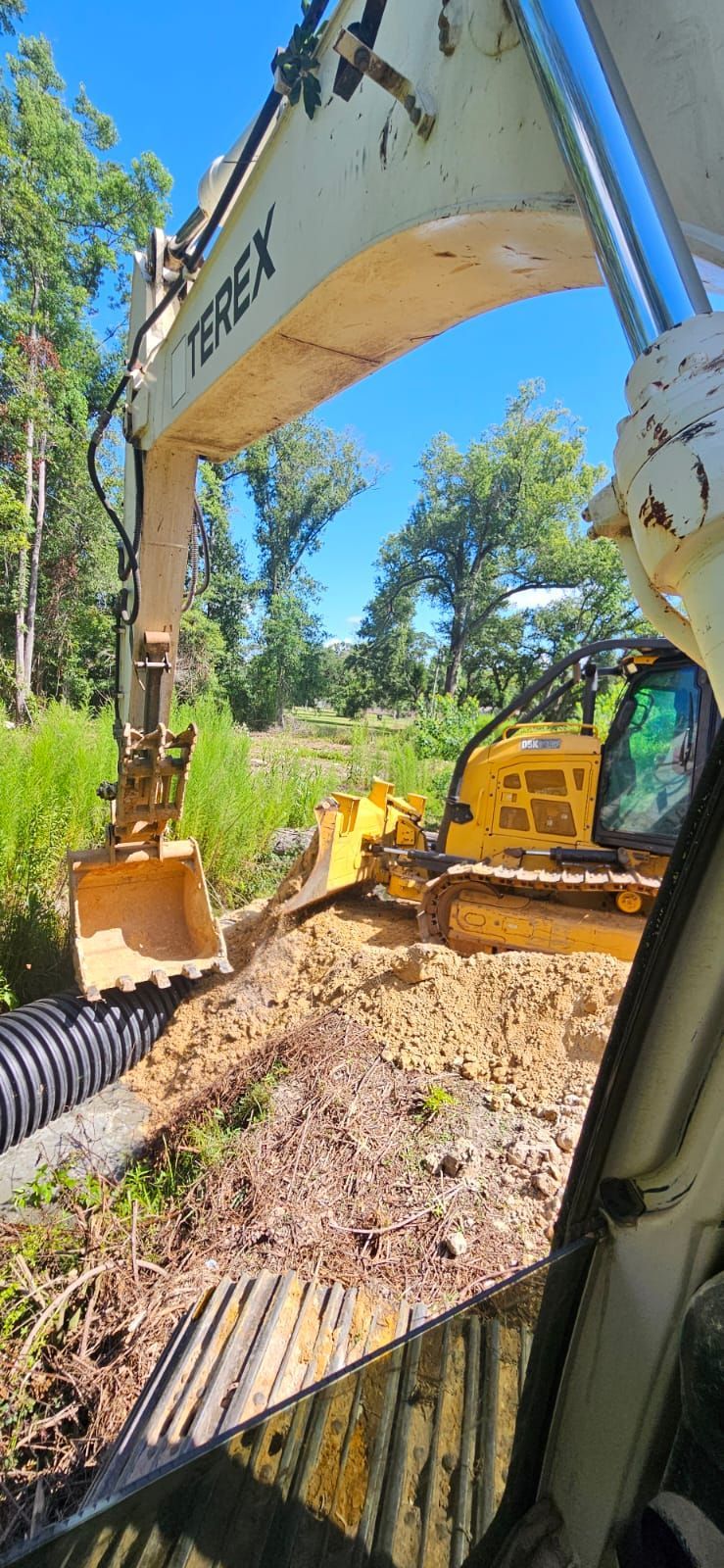 An excavator working on a construction site next to a bulldozer under a blue sky.