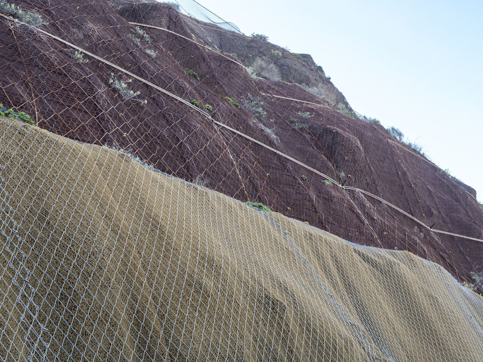Pile of muddy soil and broken concrete blocks near water.
