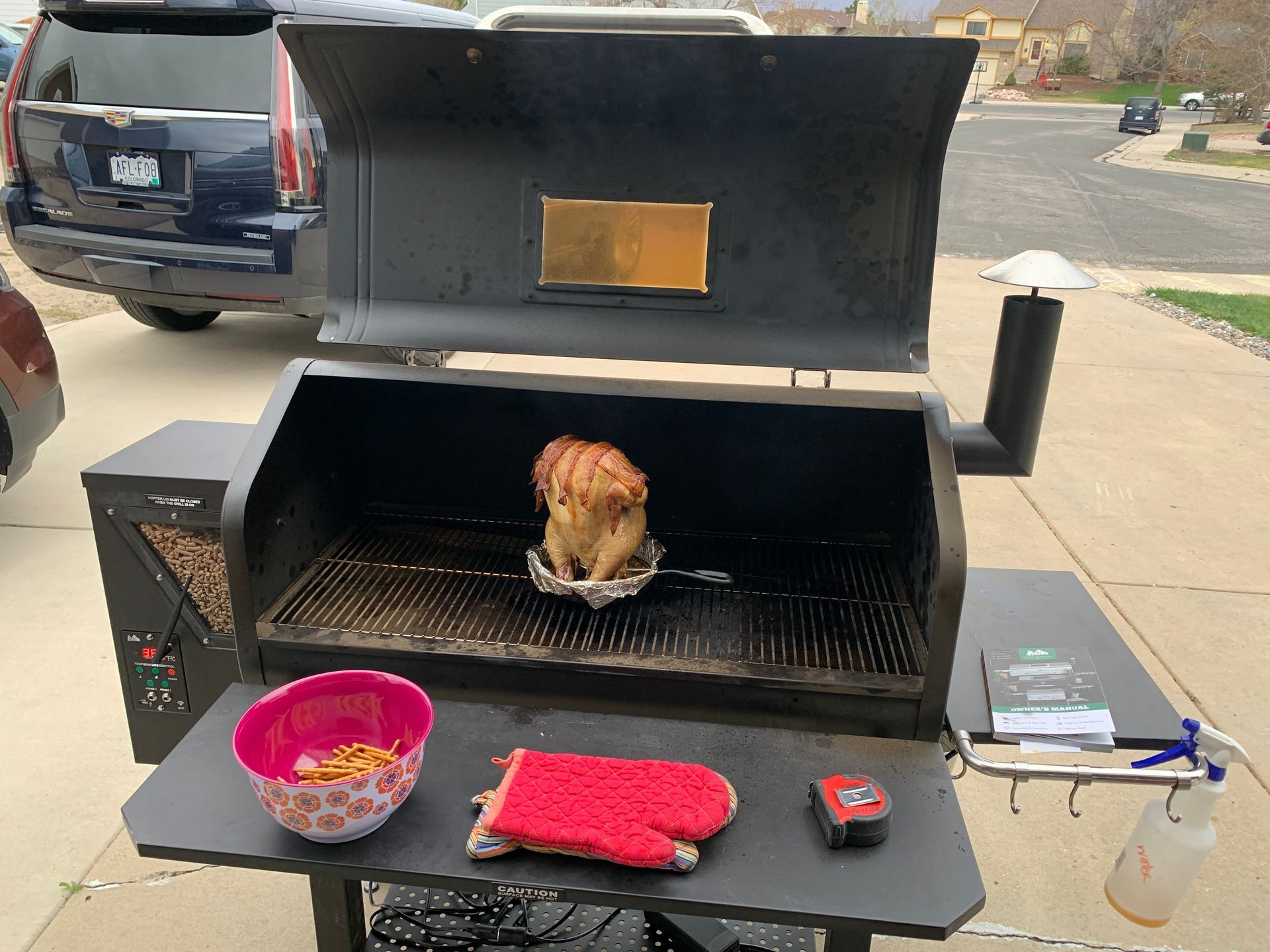A cat is sitting on top of a grill next to a bowl and gloves.
