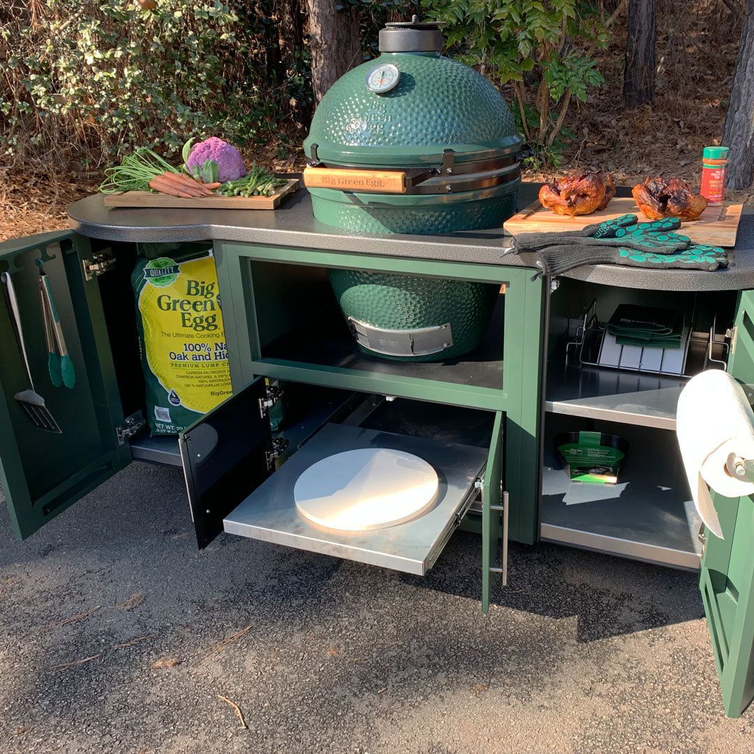A green grill is sitting on top of a green cabinet with the doors open.