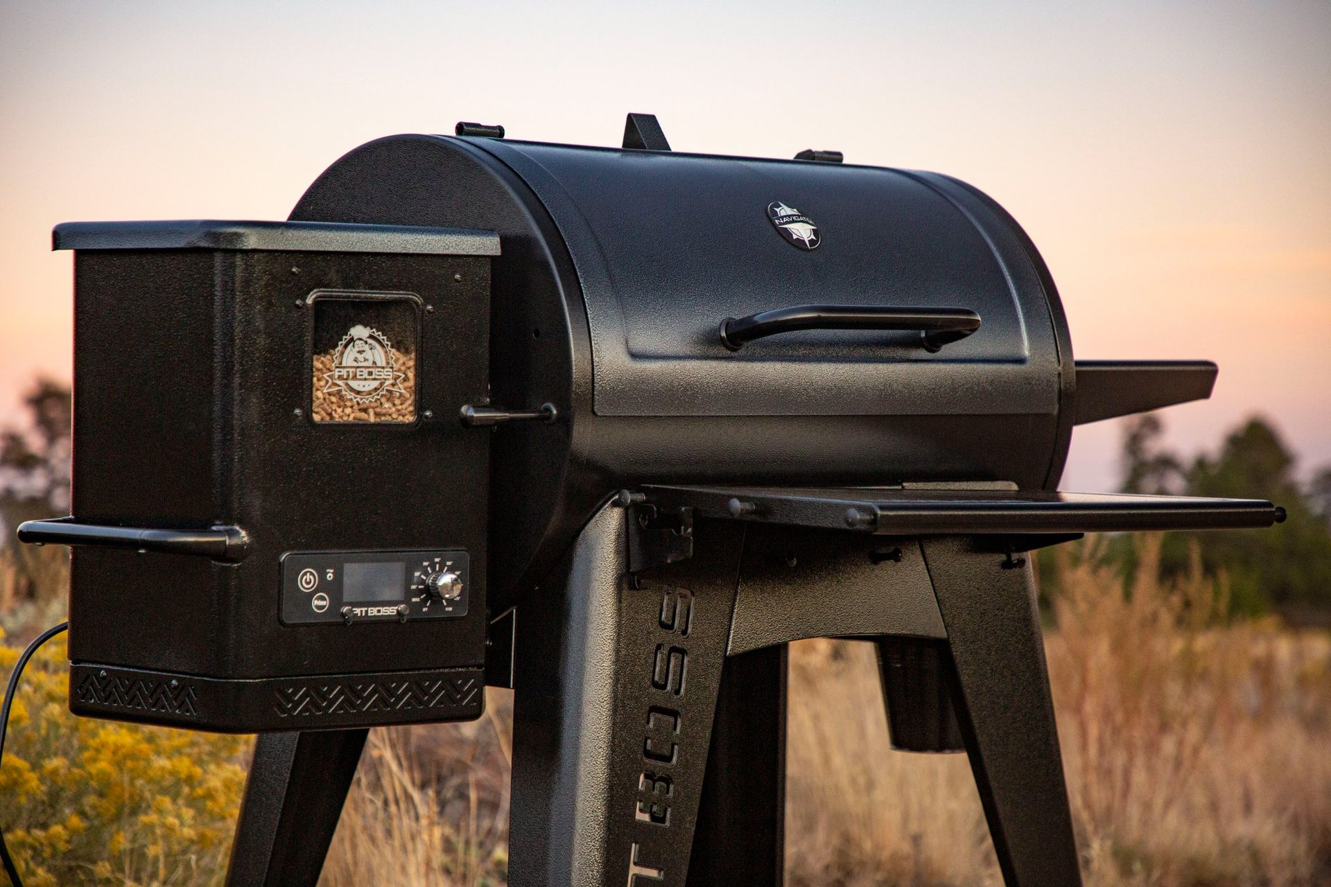 A black grill is sitting on a stand in a field.