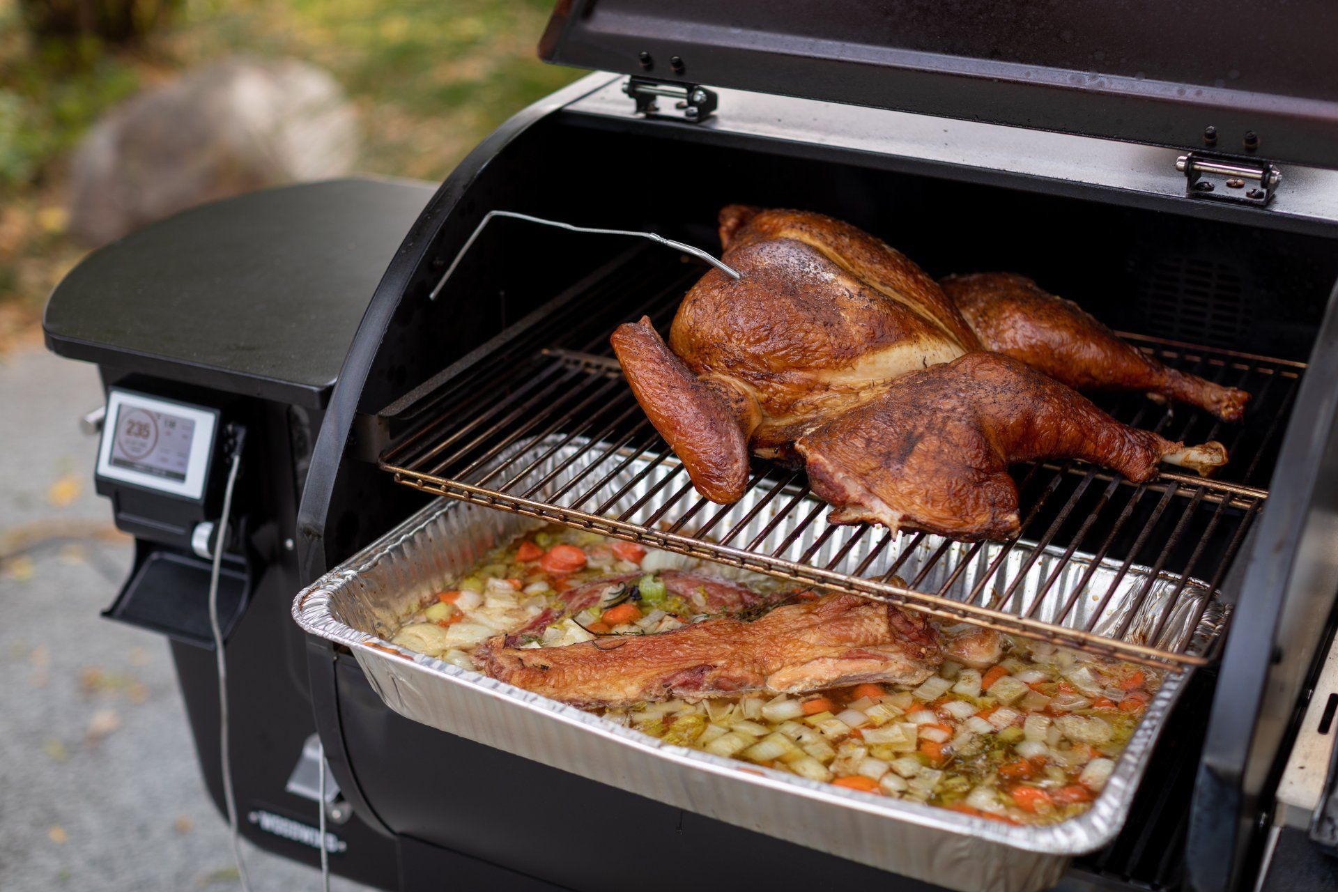 A turkey is being cooked on a grill with vegetables.