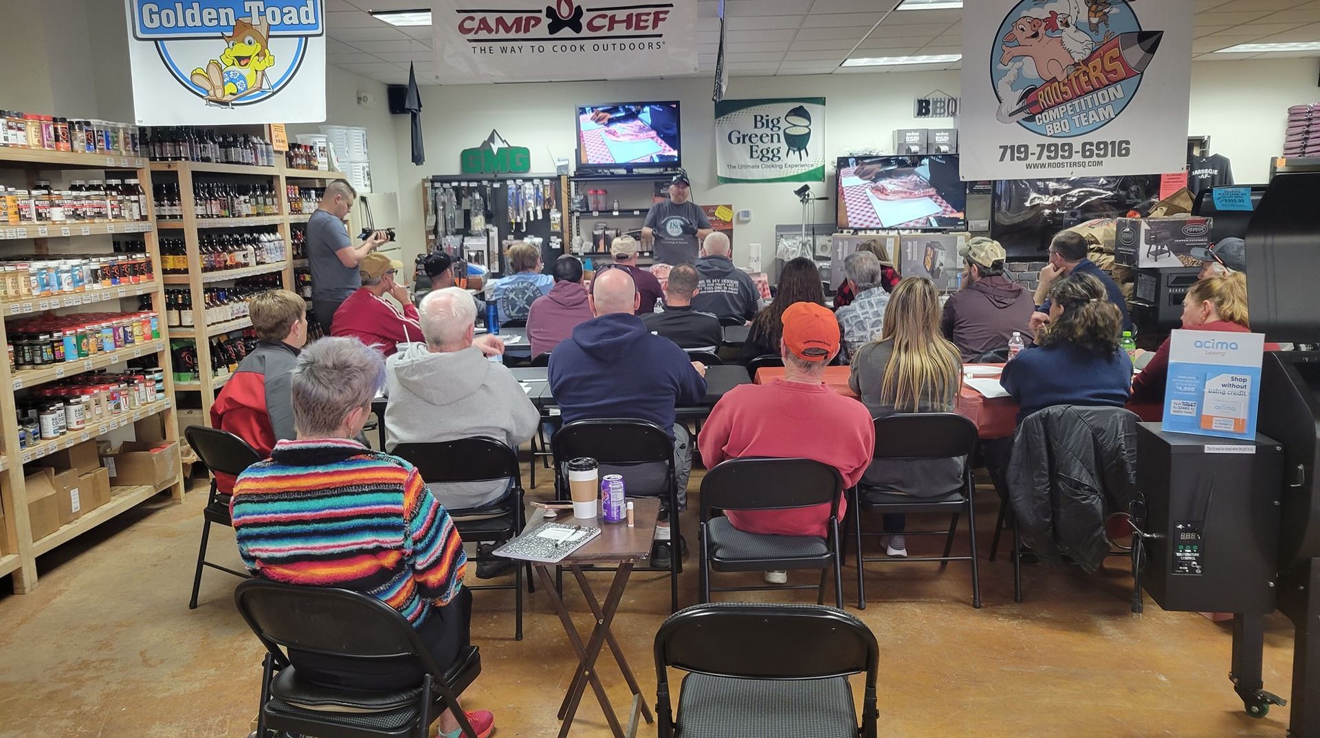 A group of people are sitting at tables in a store watching a presentation