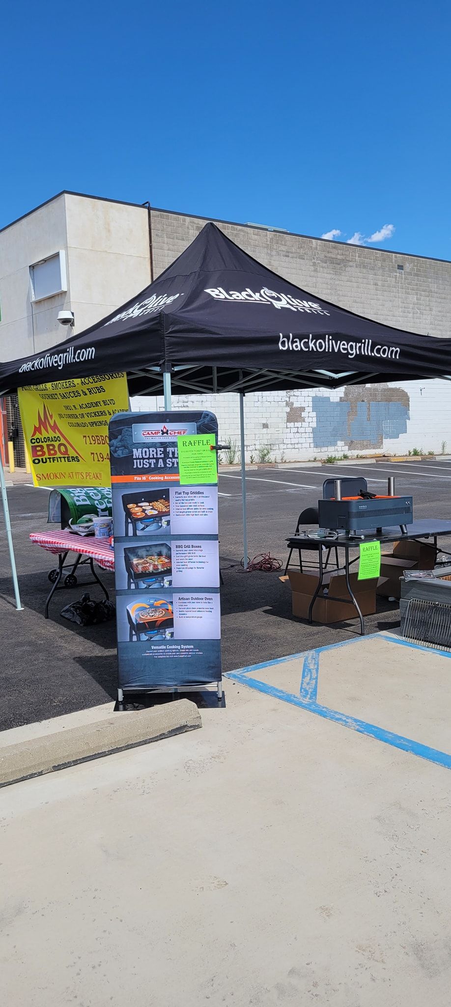 A black tent is sitting in a parking lot in front of a building.