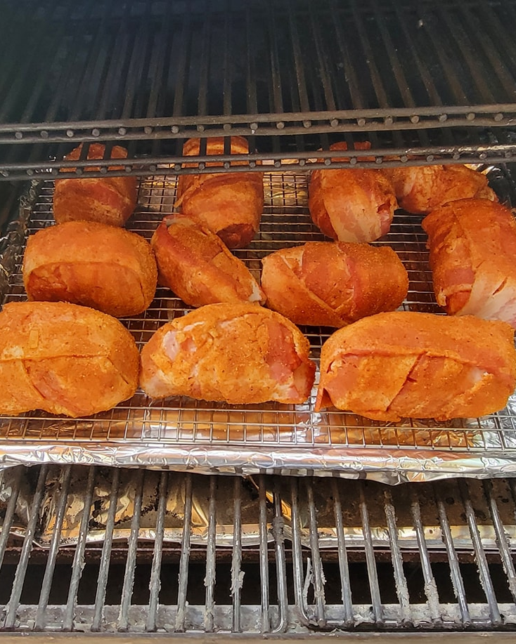 Chicken wrapped in bacon is being cooked on a grill
