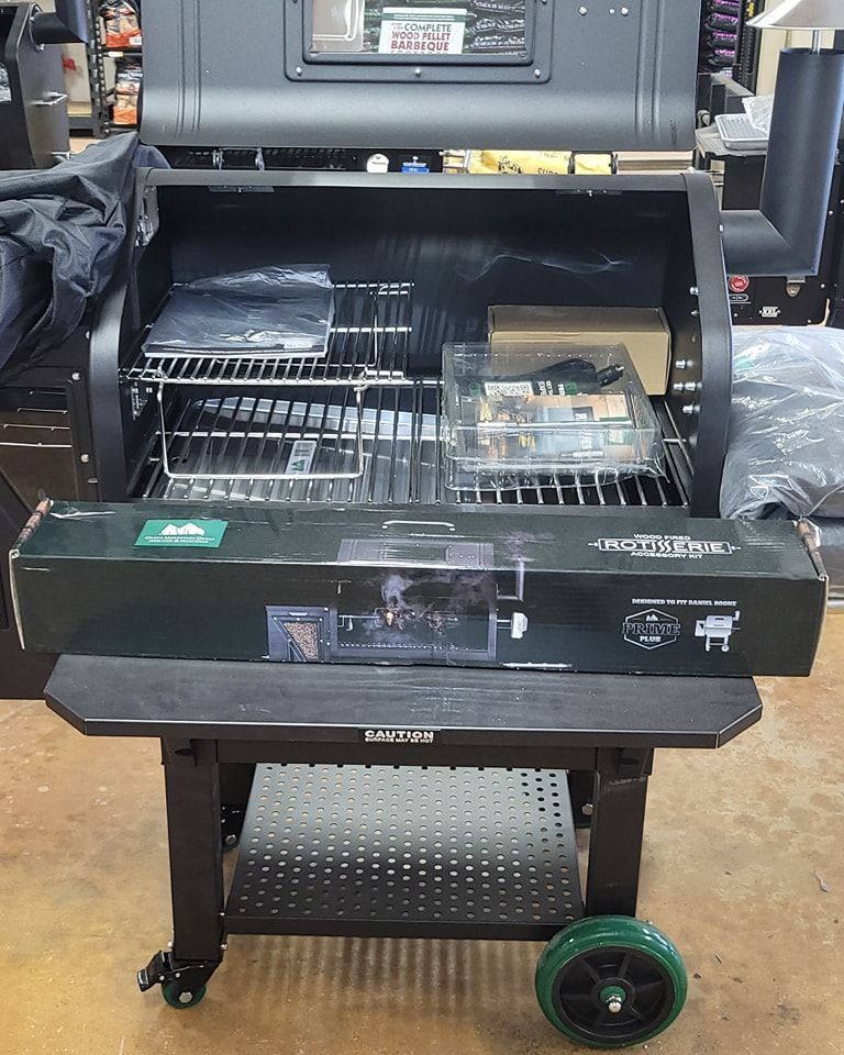 A black grill with green wheels is sitting on a table