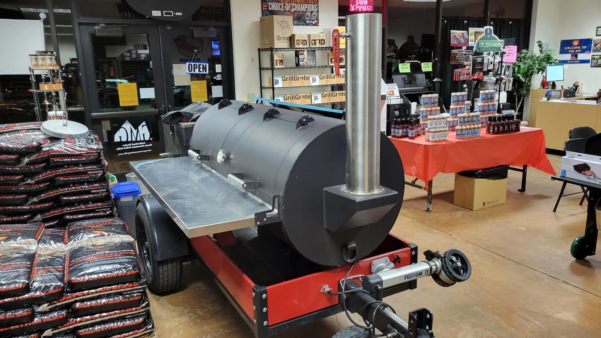 A large bbq grill is sitting on a trailer in a store.