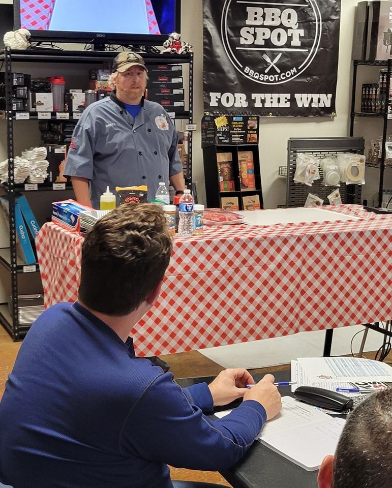 A man is giving a presentation in front of a sign that says bbq spot for the win