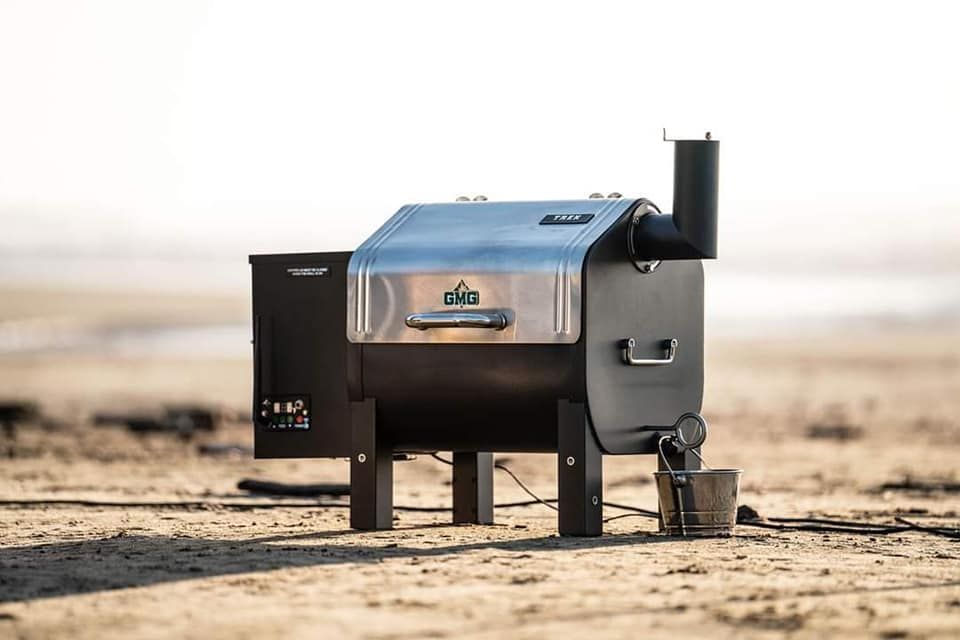 A small grill is sitting on top of a sandy beach.