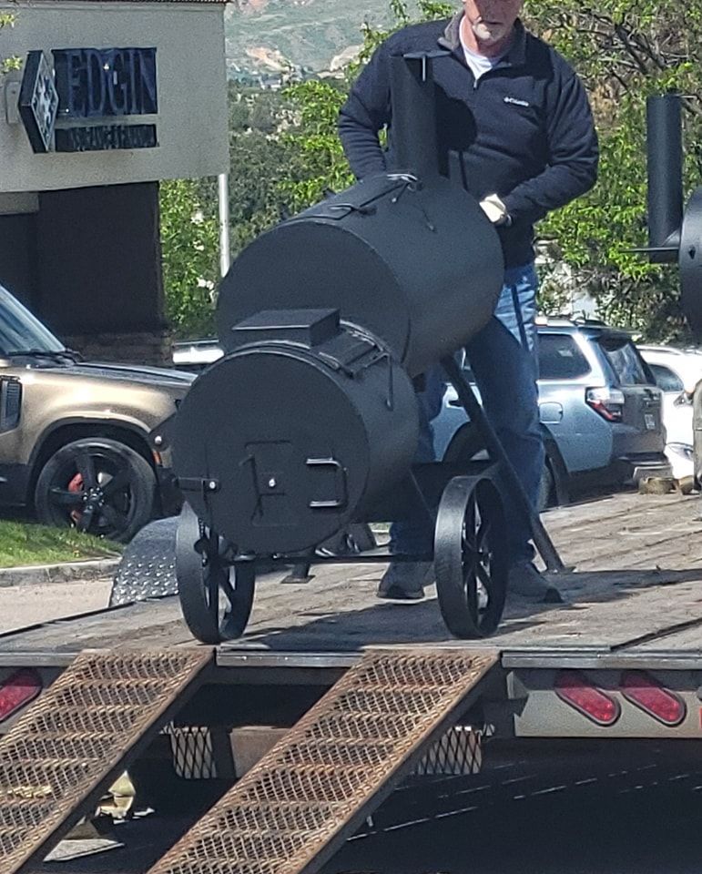 A man is pushing a large black object on wheels