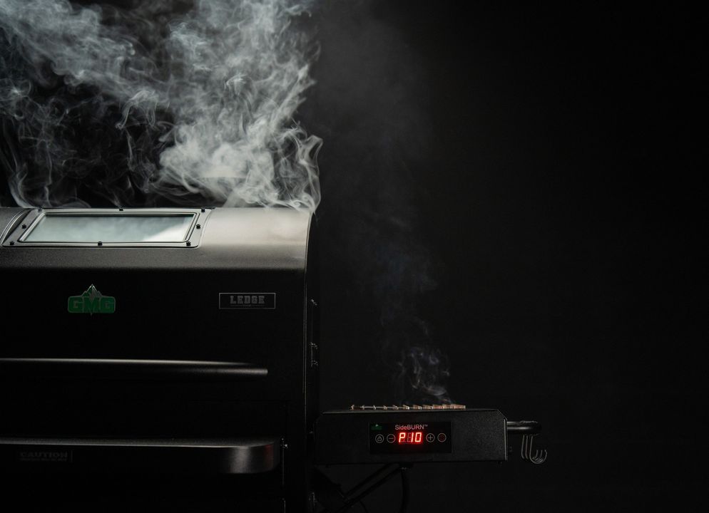 Smoke is coming out of a grill in a dark room.