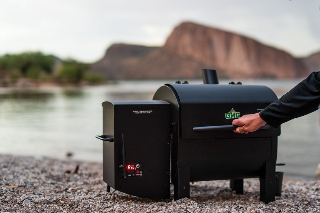 A person is cooking food on a grill on the beach.