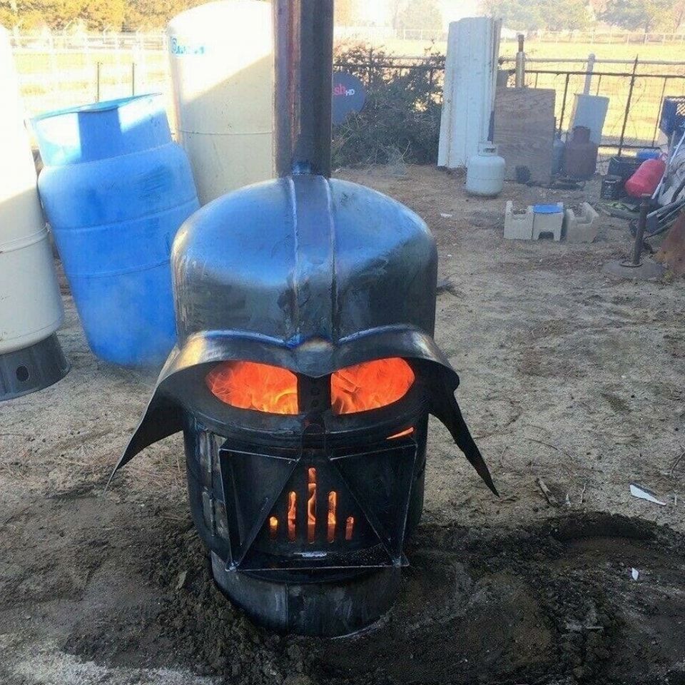 A darth vader stove is sitting in the dirt