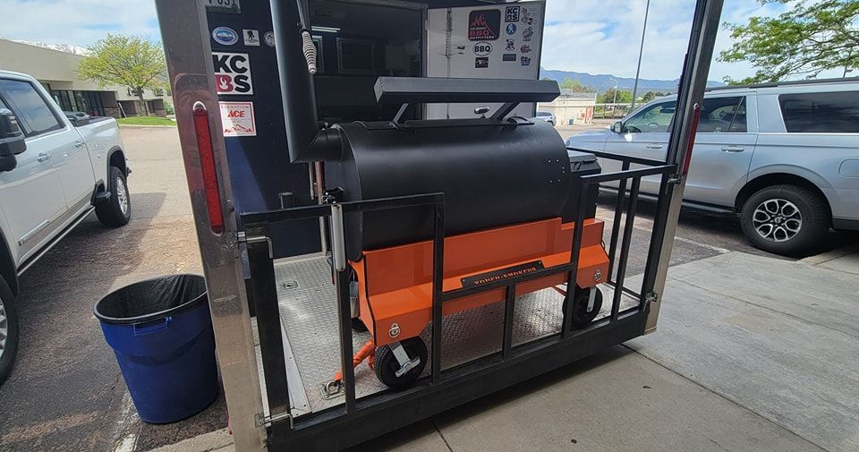 A gas pump is sitting in a parking lot next to a trash can.