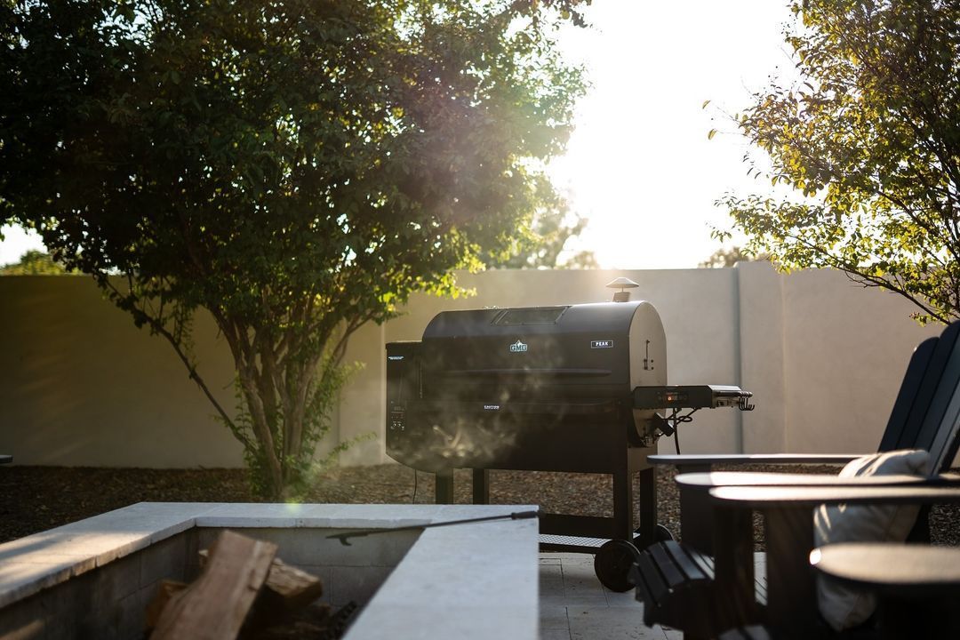 A person is sitting in a chair in front of a grill.